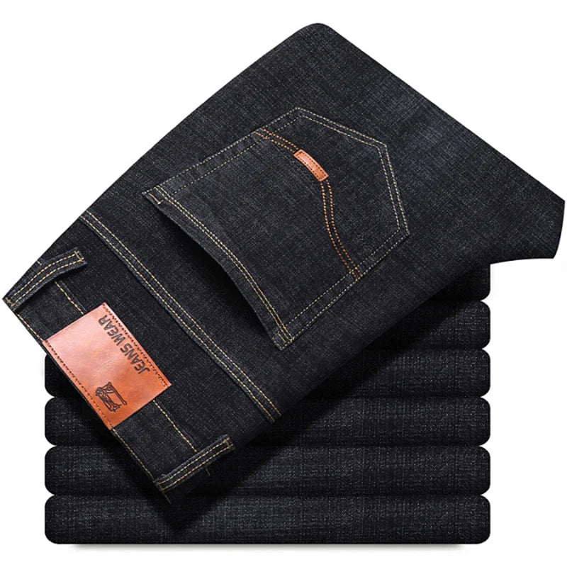 Stack of folded dark blue jeans with a brand label on a white background