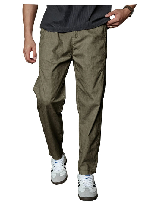 A person wearing olive green tapered pants with a dark gray ribbed t-shirt and white sneakers, shown from the waist down 