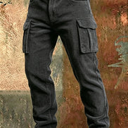 Dark gray corduroy cargo pants with flap thigh pockets and a brown belt against a textured rust-colored metal background.