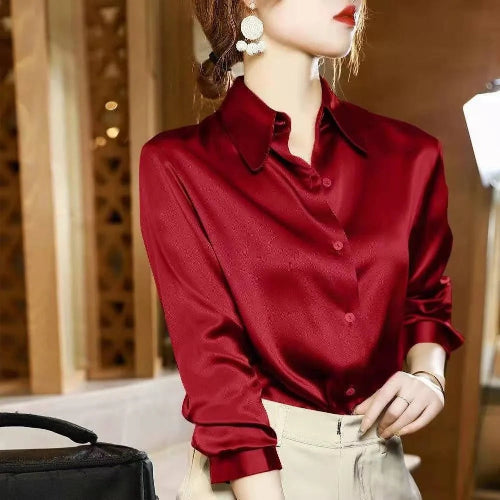 Red satin button-down shirt worn by a model with beige pants and a black bag.