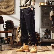 Model wearing black loose-fit cargo pants with a drawstring waist, cuffed ankles, and tan lace-up boots.