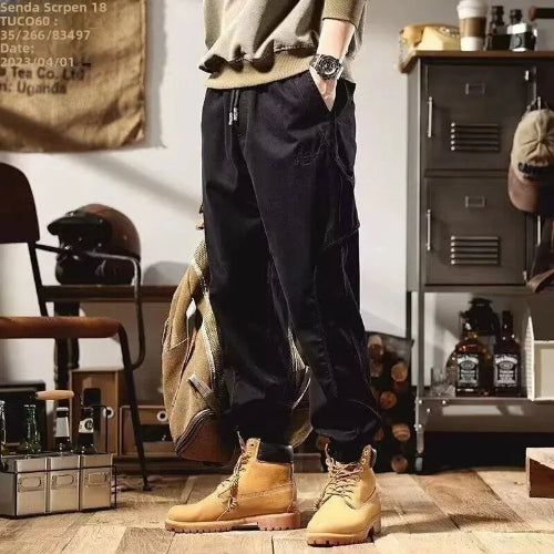 Model wearing black loose-fit cargo pants with a drawstring waist, cuffed ankles, and tan lace-up boots.