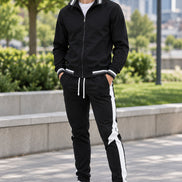 Black tracksuit with white stripes on pants and white sneakers on a white background