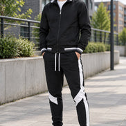 Black tracksuit with white stripes on pants and white sneakers on a white background