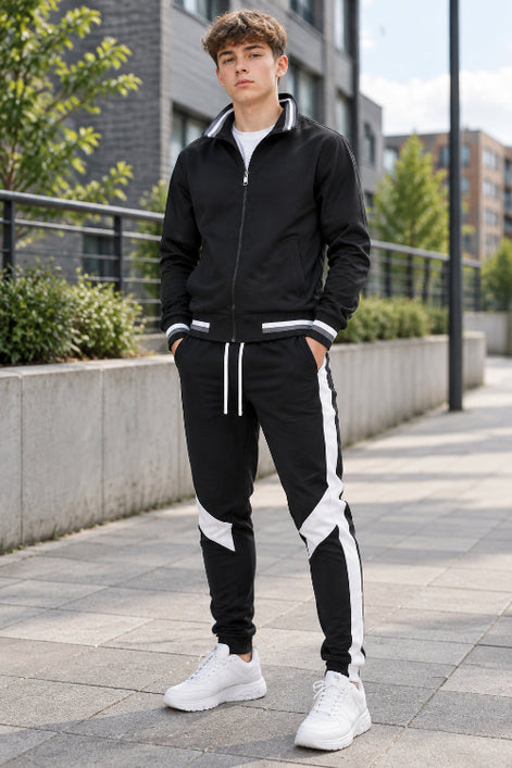 Black tracksuit with white stripes on pants and white sneakers on a white background