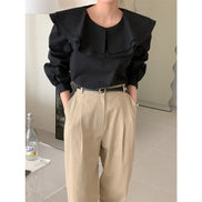 A person wearing a black long-sleeve blouse with dramatic layered ruffless