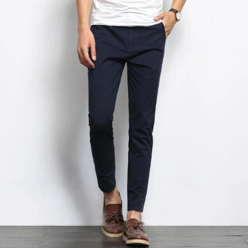 Person wearing navy pants and brown shoes against a white background