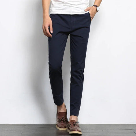 Person wearing navy pants and brown shoes against a white background
