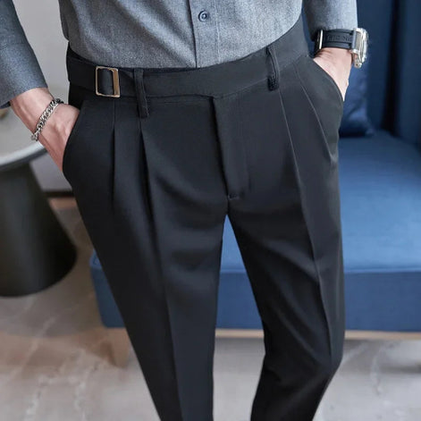 Person wearing black dress pants with a blurred indoor background