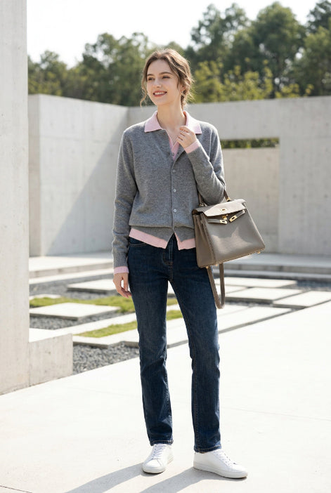 A person taking a mirror selfie wearing a gray button-up cardigan over a light pink top, paired with dark blue jeans
