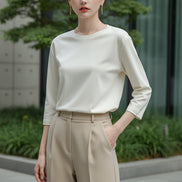 Person wearing a white long-sleeve shirt in a neutral setting
