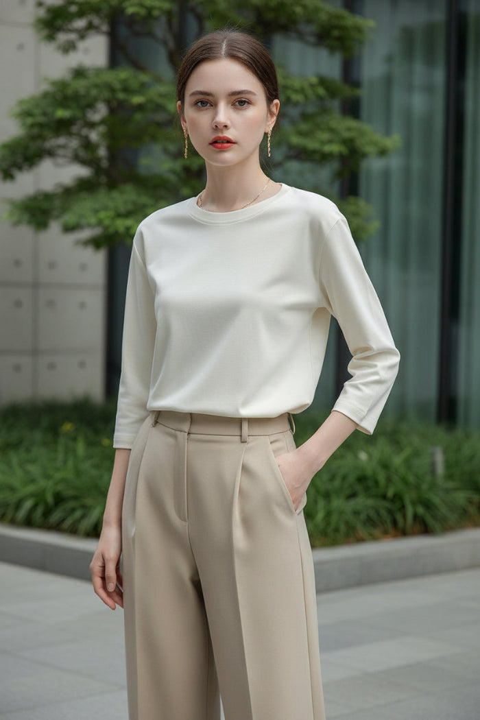 Person wearing a white long-sleeve shirt in a neutral setting