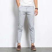 Person wearing light gray pants and brown shoes on a white background