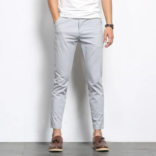 Person wearing light gray pants and brown shoes on a white background