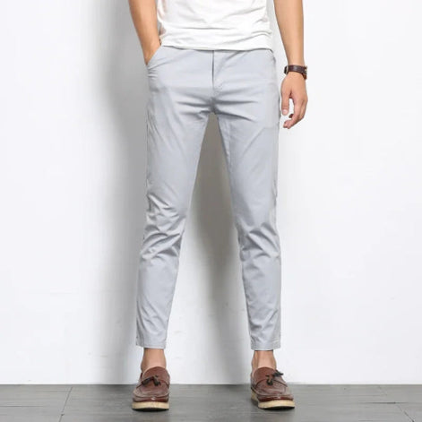 Person wearing light gray pants and brown shoes on a white background