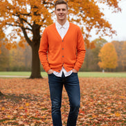 Orange cardigan over a white shirt on a wooden hanger