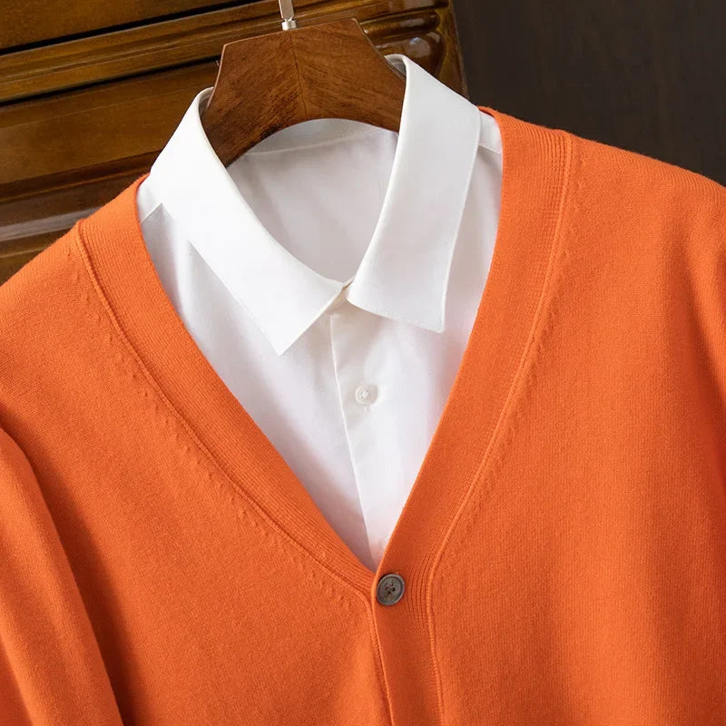 Orange cardigan over a white shirt on a wooden hanger