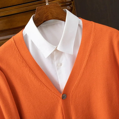 Orange cardigan over a white shirt on a wooden hanger
