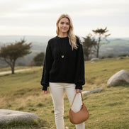 A person wearing a black cable-knit sweater with a diamond pattern, 
