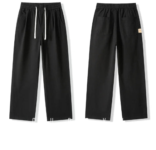 Front and back views of black straight-leg pants laid flat, showing an elastic waistband, white drawstring, slanted side pockets, and back patch pockets.