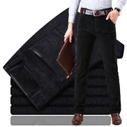 Person wearing black jeans with a stack of folded black jeans in the foreground.