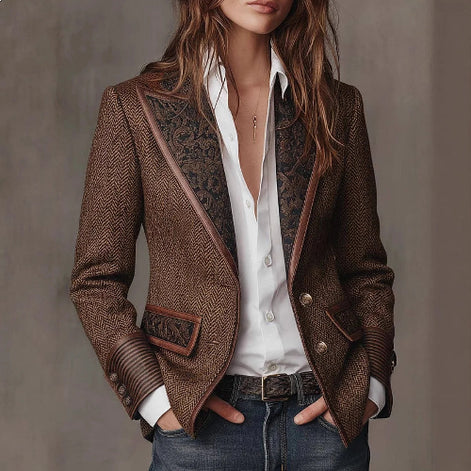 Woman wearing a brown herringbone-pattern jacket with contrast patterned lapels, pocket accents and striped cuffs over a white shirt and jeans