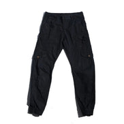 Black cargo pants laid flat against a white background, showing angled thigh pockets, buttoned flap pockets, side straps, and gathered ankle cuffs.