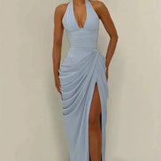 A woman modeling a light blue halter-neck maxi dress with a deep V-neckline, draped skirt details, and a high thigh slit, 