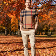 Plaid patterned sweater with a mix of brown, red, and black colors on a gray background.
