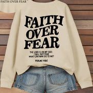 Beige sweatshirt with 'Faith Over Fear' text on a wooden background