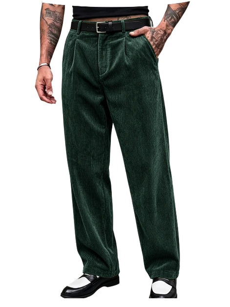 A person wearing dark green corduroy trousers with a black belt, paired with black and white shoes, shown from the waist down on a plain white background.