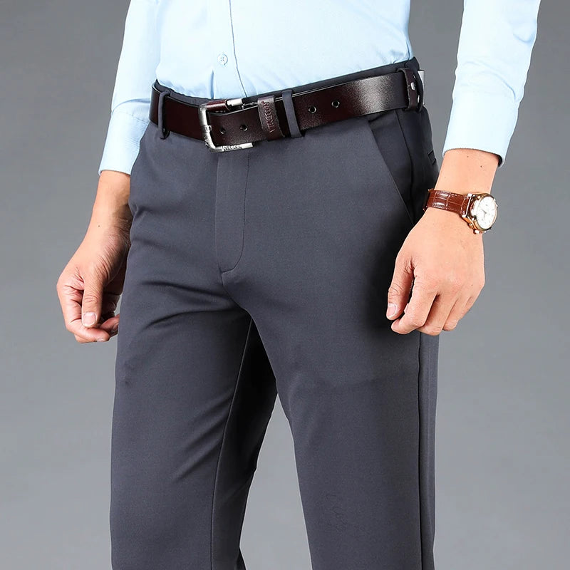 Person wearing gray pants, light blue shirt, brown belt, and watch on a gray background