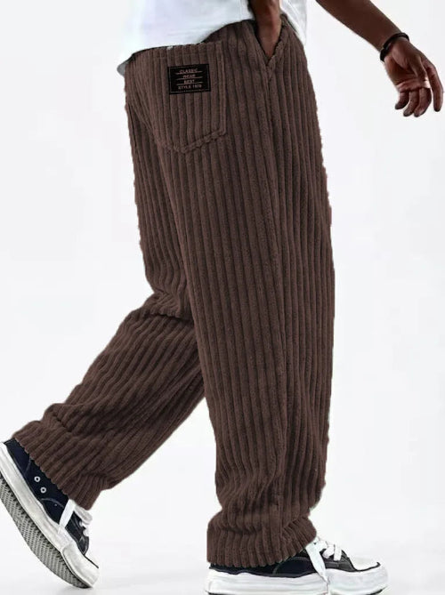 Brown corduroy pants worn by a person on a white background