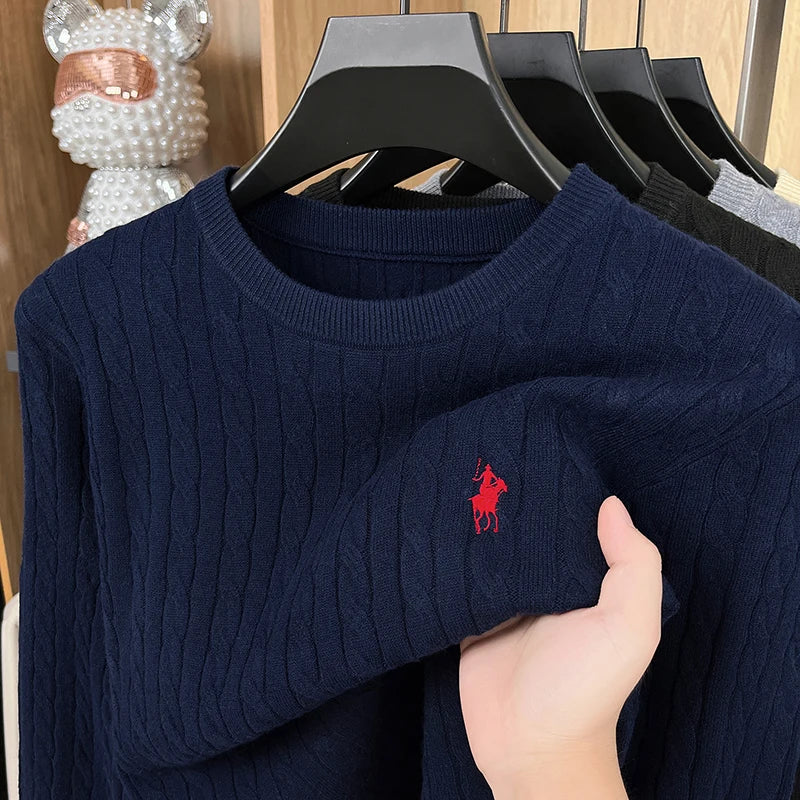 Navy blue sweater with a red logo held by a hand on a wooden background