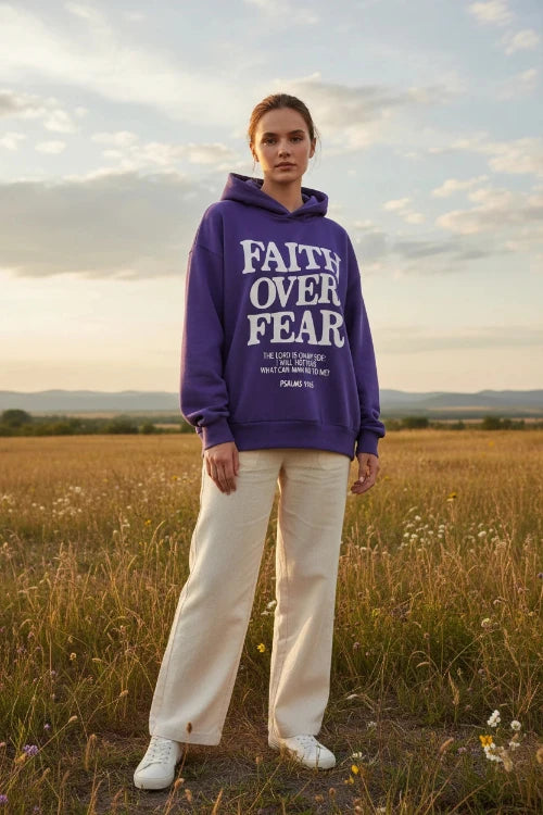 Purple hoodie with 'Faith Over Fear' text on a wooden surface