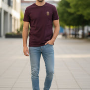 Maroon t-shirt with a small logo on a hanger against a light background