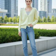 A person wearing a pale pastel yellow fuzzy V-neck cardigan over a gray ribbed top, 