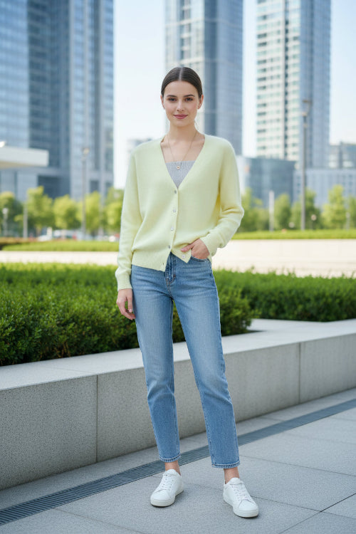 A person wearing a pale pastel yellow fuzzy V-neck cardigan over a gray ribbed top, 