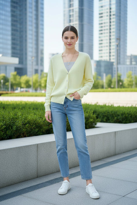 A person wearing a pale pastel yellow fuzzy V-neck cardigan over a gray ribbed top, 