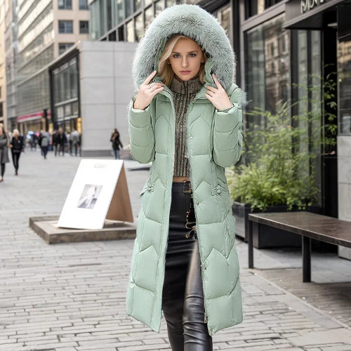 Woman wearing a long green puffer coat with a fur-lined hood on a city street.
