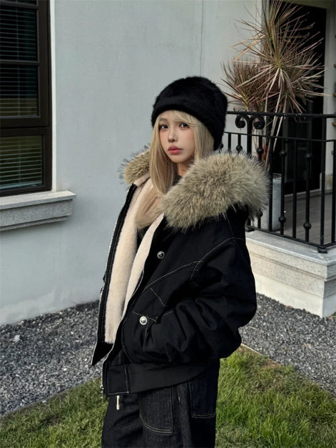 Person wearing a black coat with a fur-lined hood outdoors.