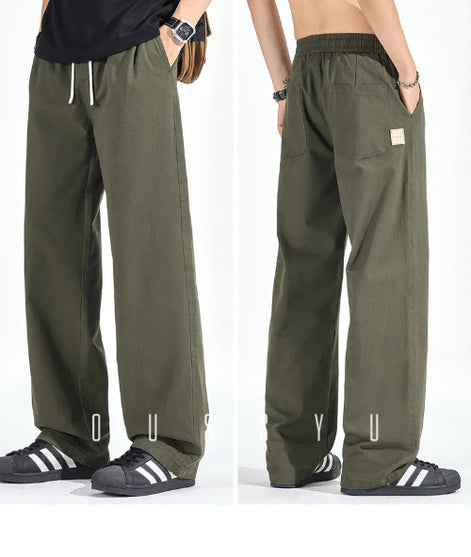 Front and back views of a model wearing army green loose-fit straight-leg pants, showing a white drawstring, elastic waistband, side pockets, and back patch pockets.