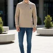 Beige long-sleeve polo shirt with a brand logo on a hanger against a clothing rack background.