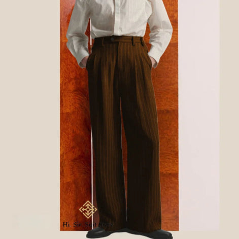 Brown pleated pants worn with a white shirt against a wooden panel background