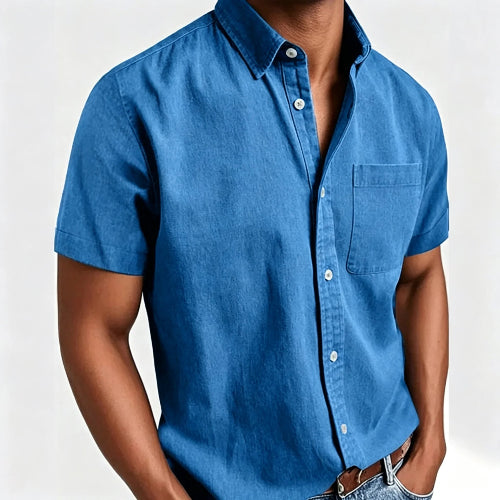 A man wearing a blue short-sleeve button-up shirt with a chest pocket, shown from the neck down against a plain light background.