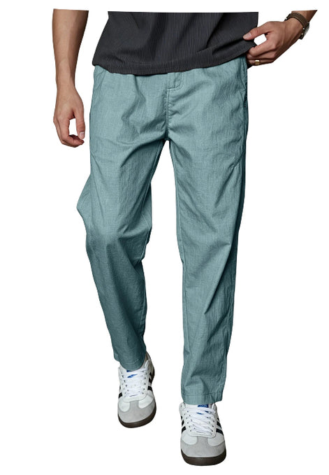 A person wearing teal-blue relaxed-fit pants with a dark gray ribbed t-shirt and white sneakers, shown from the waist down against a plain white background.