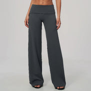 A model wearing dark gray wide-leg yoga pants with a double waistband, shown from the waist down against a light gray studio background.