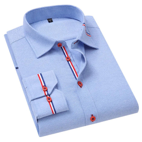 A light blue long-sleeve dress shirt folded neatly, featuring red and blue striped button accents on the collar, placket, and cuff, with red buttons.
