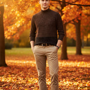 Person wearing a brown sweater over a white shirt with beige pants against a gray background