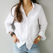 White long-sleeve button-down shirt worn by a model standing against a wall.